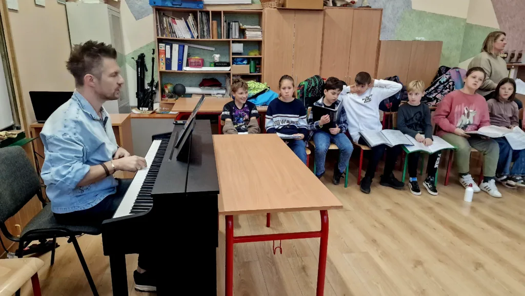 Dzieci podczas warsztatów Most the Music. Adam Sztaba przy instrumencie klawiszowym.