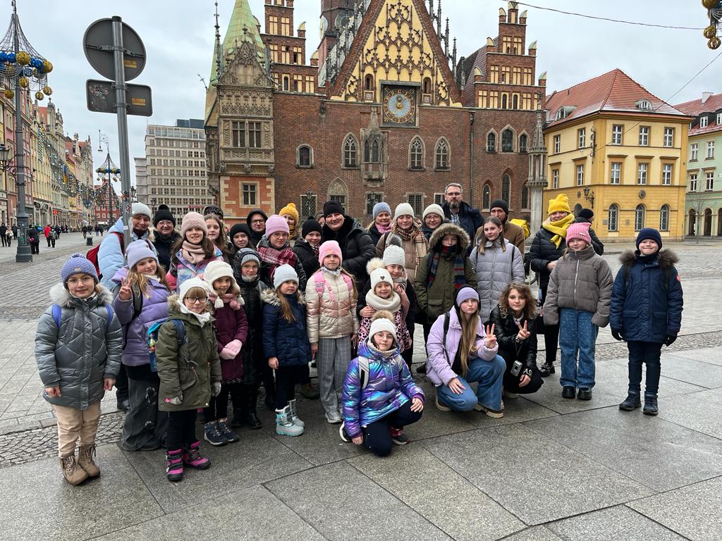 Zdjęcie grupowe: dzieci, młodzież i chórmistrzowie Most the Music na rynku we Wrocławiu.