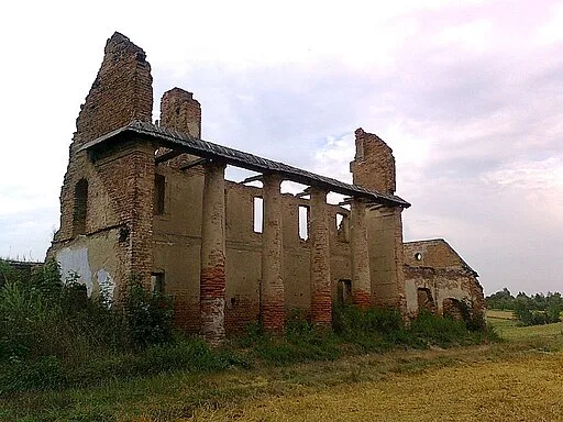 Zdjęcie przedstawia ruiny oranżerii. Budynek z cegły, pozbawiony ściany.