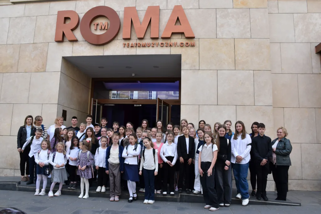 Grupa dzieci i młodzieży - zdjęcie grupowe przed teatrem roma