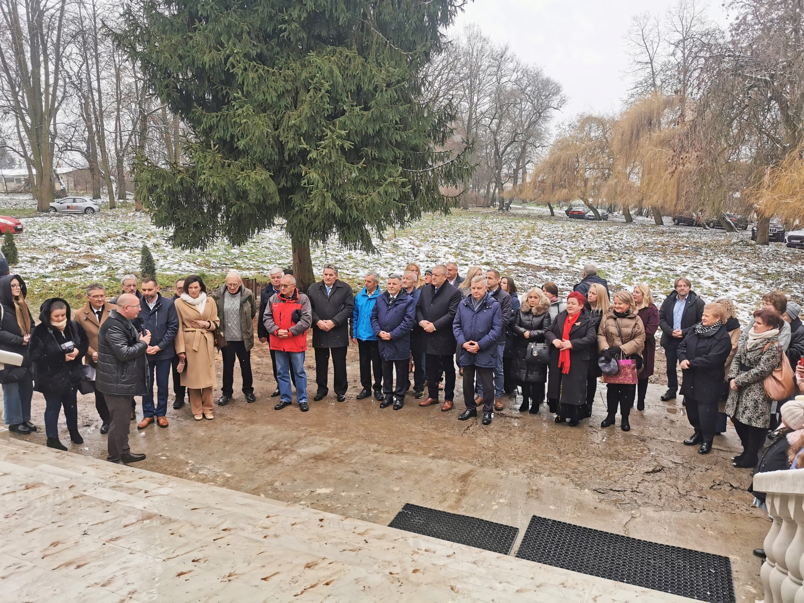 Grupa ponad dwudziestu osób przed wejściem do budynku.